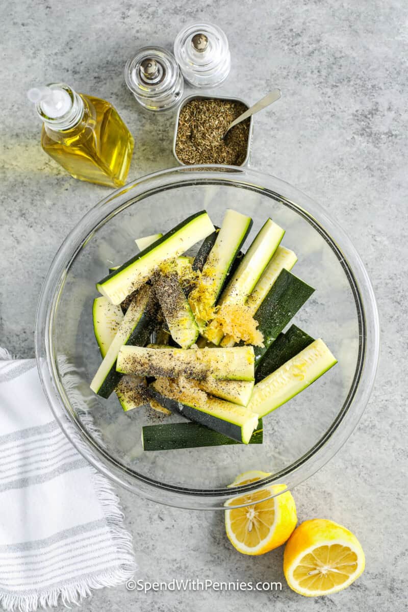 adding ingredients to zucchini to make Easy Roasted Zucchini