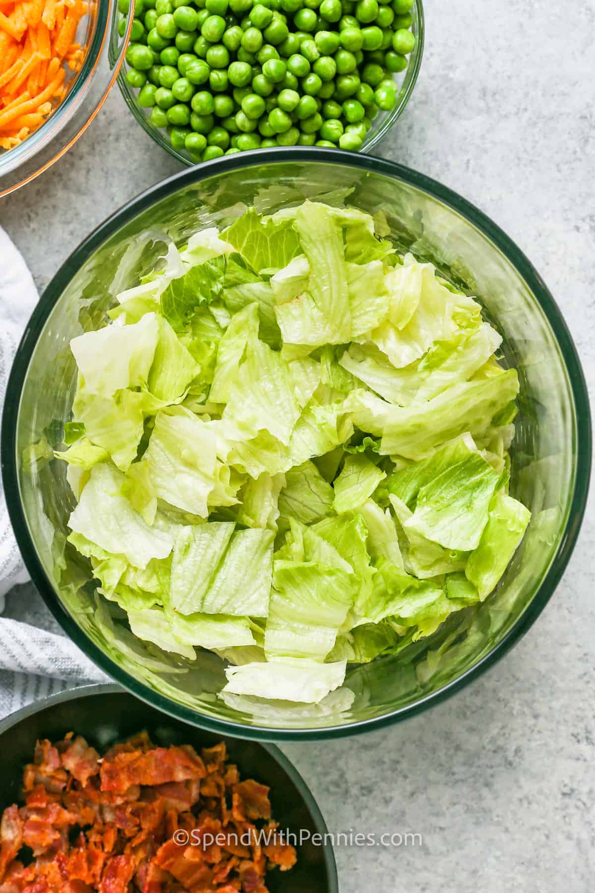 adding lettuce to bowl to make 7 Layer Salad