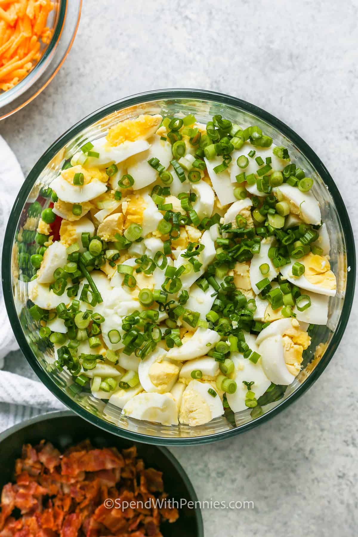 adding green onions to bowl to make 7 Layer Salad