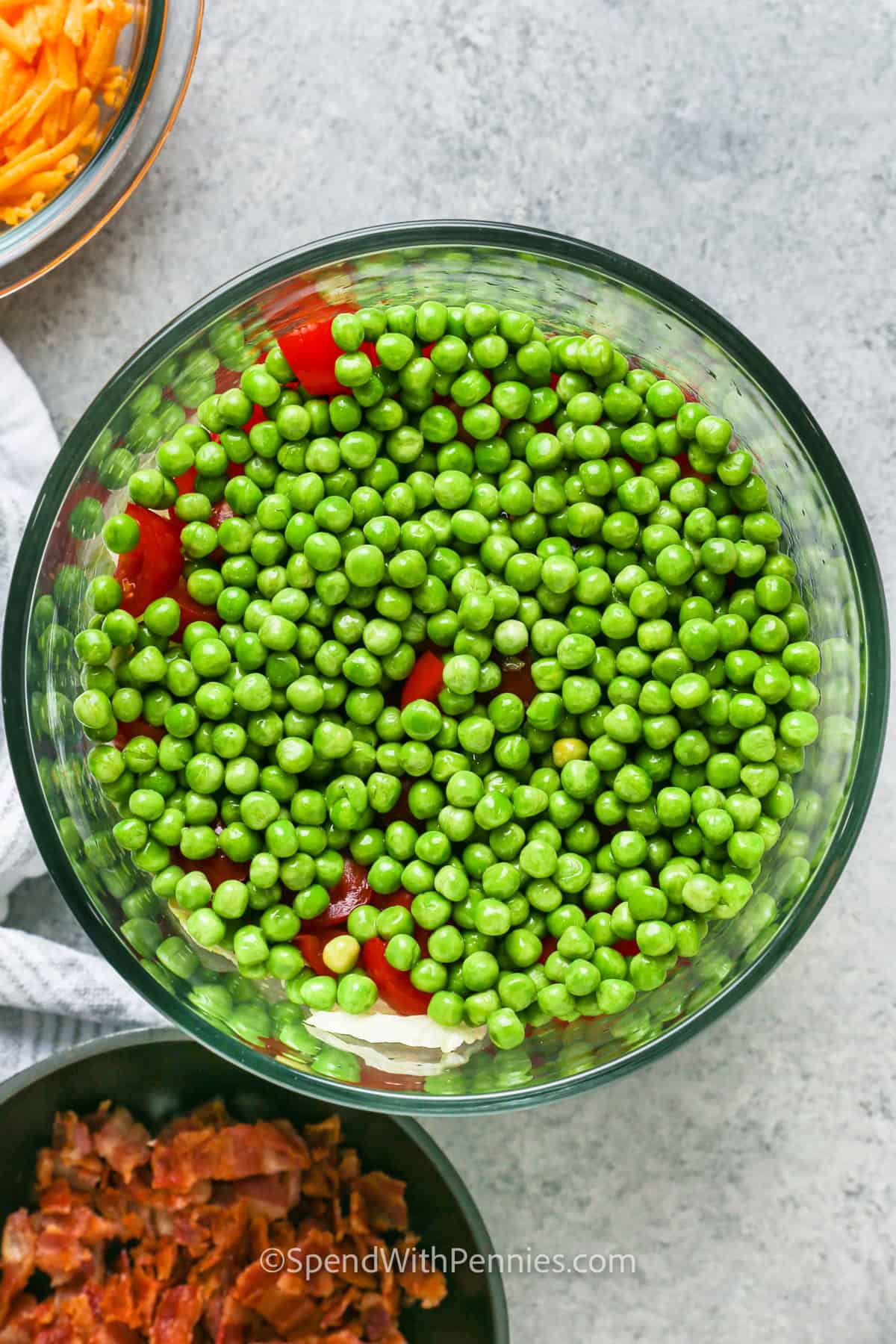 adding peas to bowls to make 7 Layer Salad