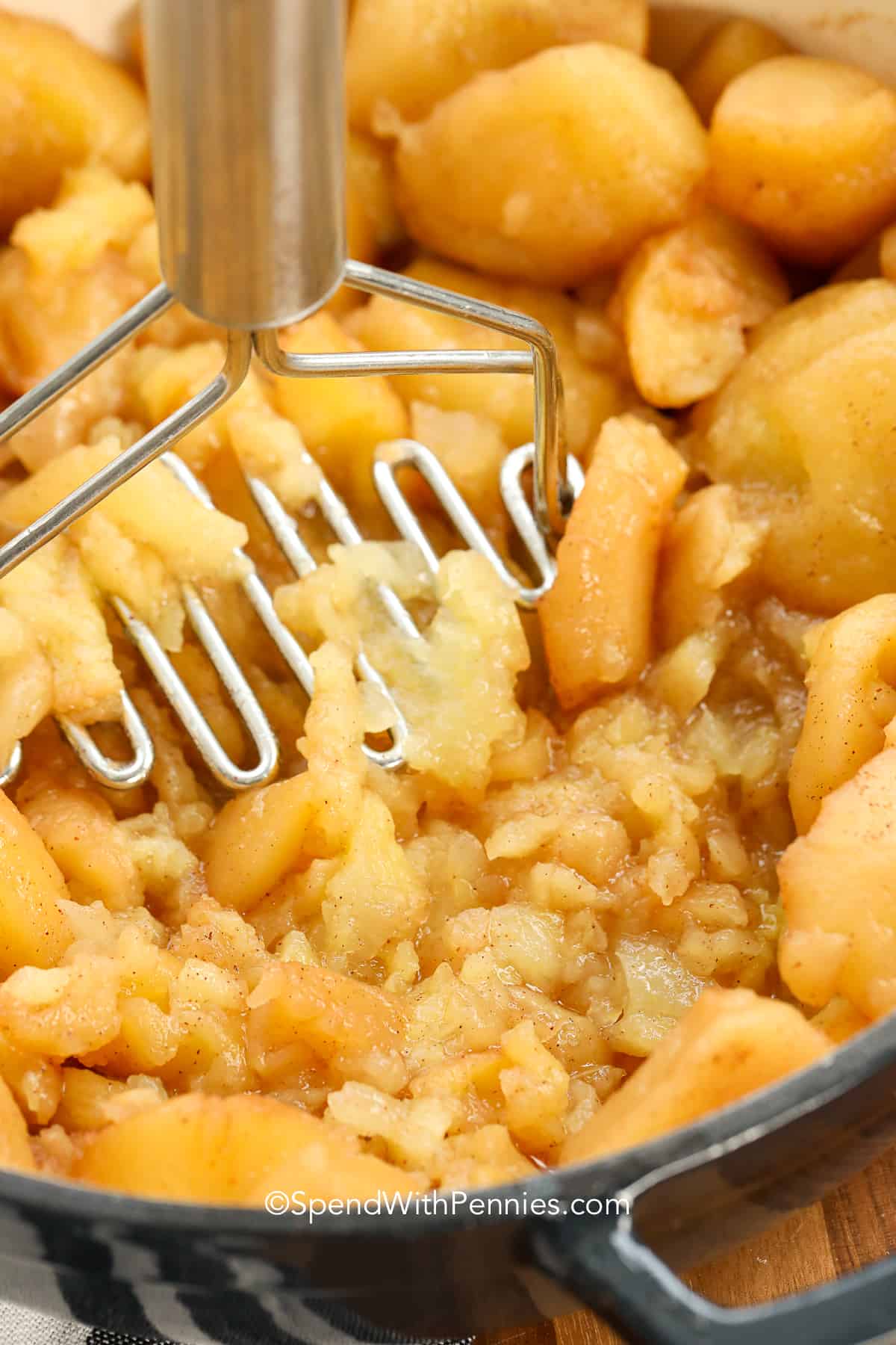 cinnamon apples being mashed in a dutch oven