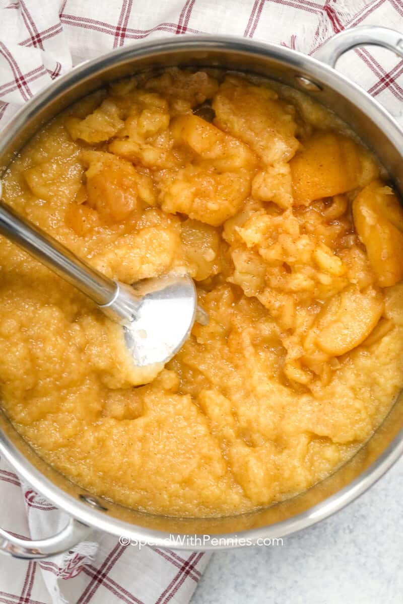 cinnamon apples being blended with a hand blender in a pot