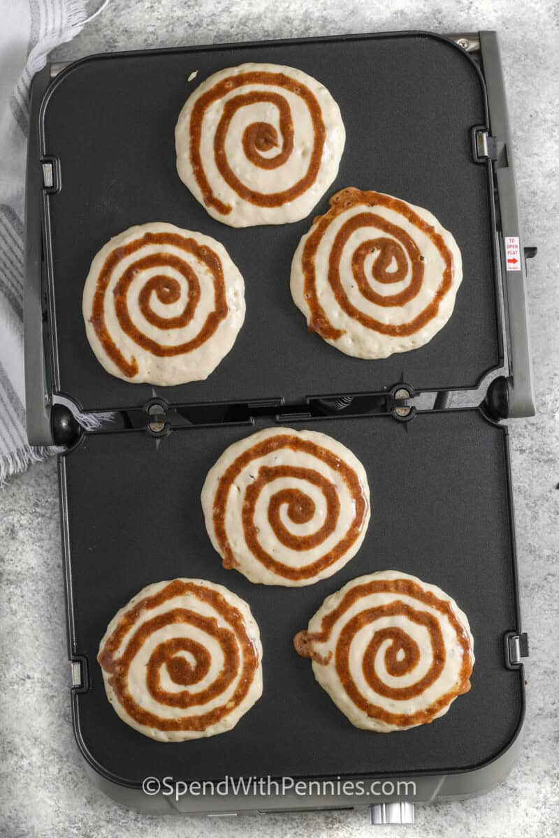 top view of Cinnamon Roll Pancakes cooking on a grill