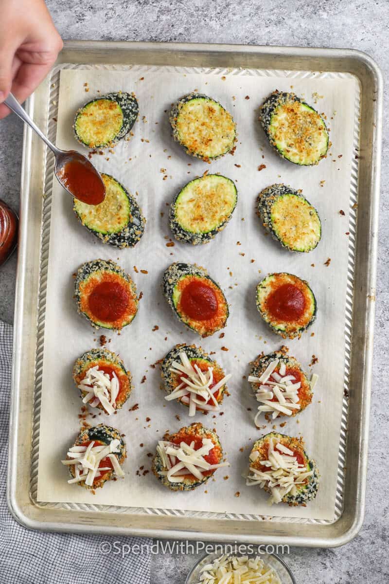 adding marinara and mozzarella to zucchini pieces to make Zucchini Parmesan