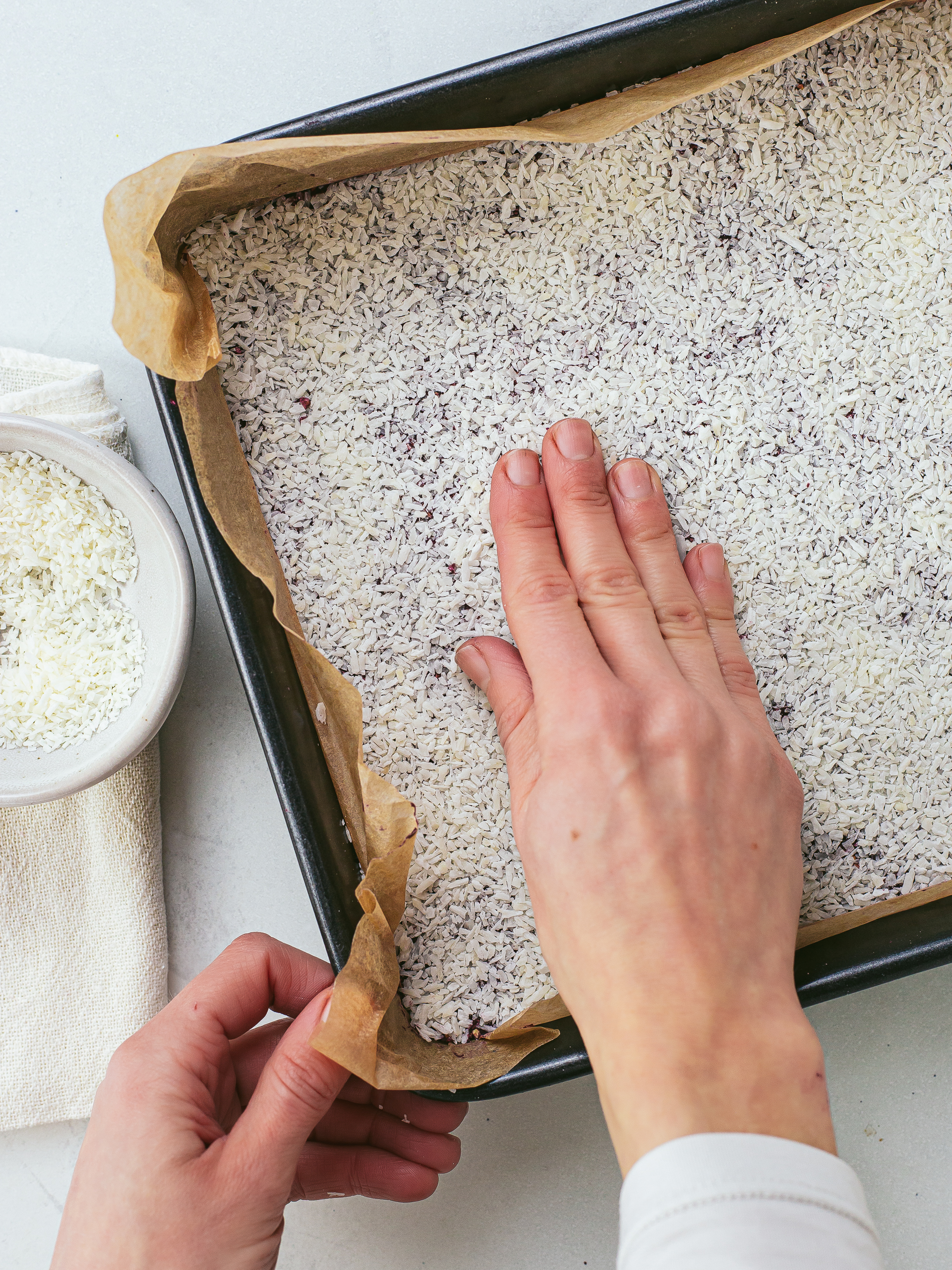 shredded coconut spread over flapjack dough in a tray